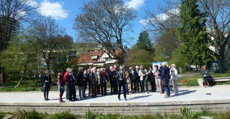 Gruppenbild im grünen. Mehrere Personen stehen auf einem Fußgänger Weg.